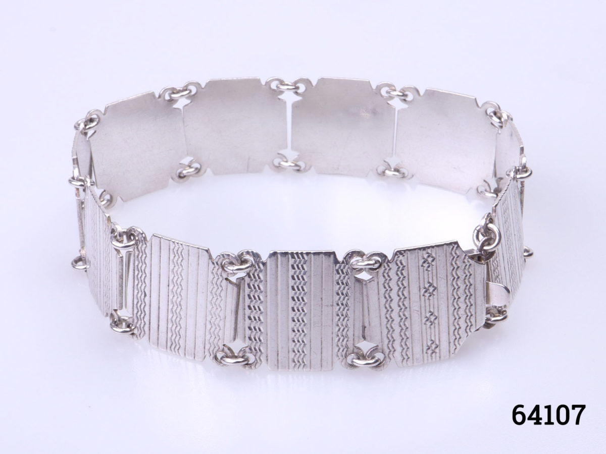 Art Deco sterling silver panel bracelet with engine turned design on each panel. Hallmarked silver. Photo of bracelet on a flat surface