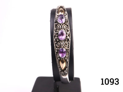 Vintage 925 Sterling silver cuff bangle. 3 oval cut amethysts nestled in fine scrollwork design to the centre and rose gilt accent either side of the stones. Main photo of bangle on display stand with only decorative side visible