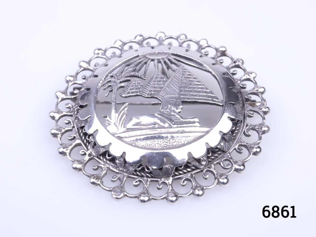 Vintage Egyptian 800 grade silver brooch. Egyptian revival piece decorated with scene of Pyramids & Sphinx. Measures 46mm in diameter Photo of brooch from a base up angle