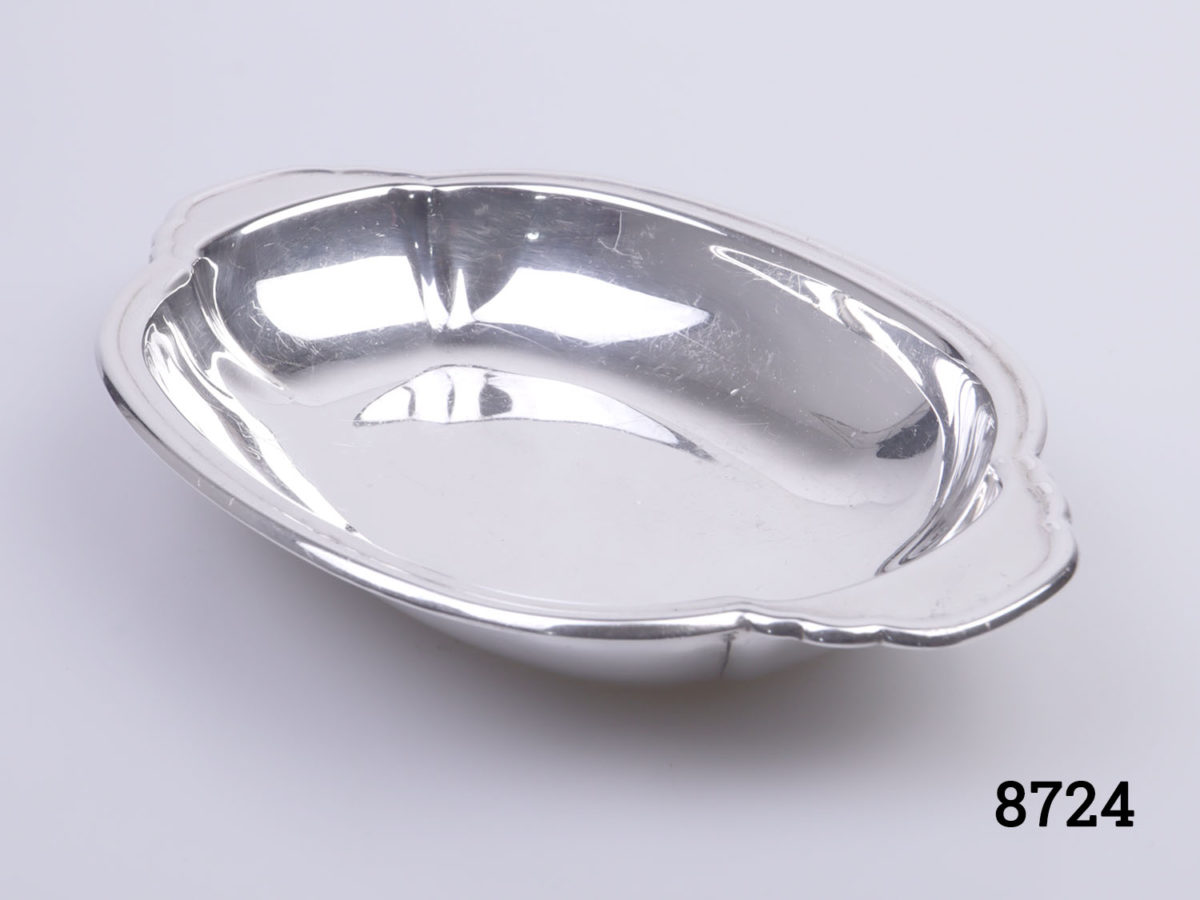 c1946 London assayed sterling silver trinket dish. Oval shaped dish with handles to the ends. Made by Louis Simpson Ltd Fully hallmarked to the base with Rd Number Photo of dish from side angle showing clear view of inside dish