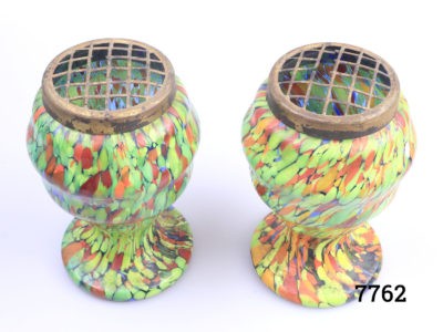 Pair of Art Deco splatter glass posy vases. Some damage to the brass frogs. Each measures 78mm in diameter at base, 90mm in diameter at widest area and 135mm tall.  Photo of both vases side by side and seen from a slight raised angle showing the brass frogs at the top with damage visible