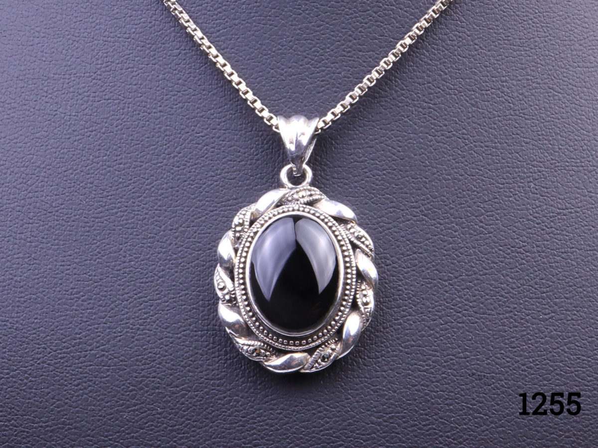 Vintage sterling silver box chain necklace with a sterling silver and black onyx pendant. Pendant drop length approximately 35mmand width 22mm Close up photo of the pendant front against the dark display stand