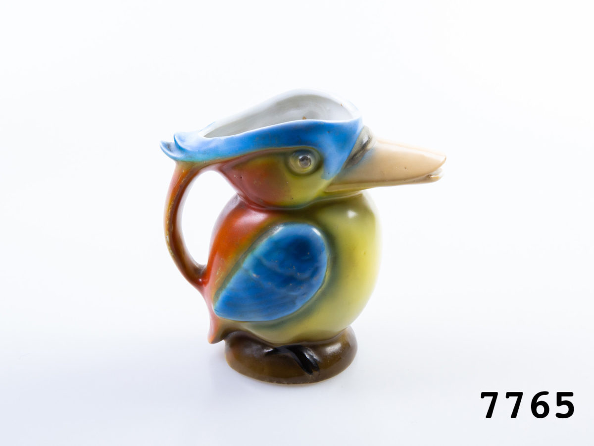 1940s vintage creamer jug in the form of a colourful Kingfisher bird. Colourful jug in the form of a toucan with beak as spout. Measures 62mm in diameter at base and 125mm at widest point from spout tip to handle edge. Photo of Kingfisher from a side angle with beak to the right and handle to the left of picture