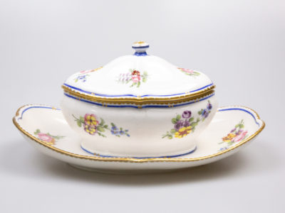 18th Century Sevres sauce boat. Soft paste porcelain sauce boat hand-painted in the feuille de choux pattern. Hairline crack to the inside of the sauce boat which does not come through under the plate. Interlaced L mark of Sevres to the base with double letter a denoting 1778. Main photo of boat with lid in place and shown from an eye level angle from the side