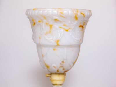 1930s Art Deco lamp with Bakelite base. Small up-lighting lamp with marble effect glass shade in cream with caramel coloured flecks on a moulded brown/black Bakelite base. Base measures 128mm in diameter and top of lamp measures 132mm in diameter. Close up photo of the cream and caramel coloured glass lampshade seen from an eye level angle.