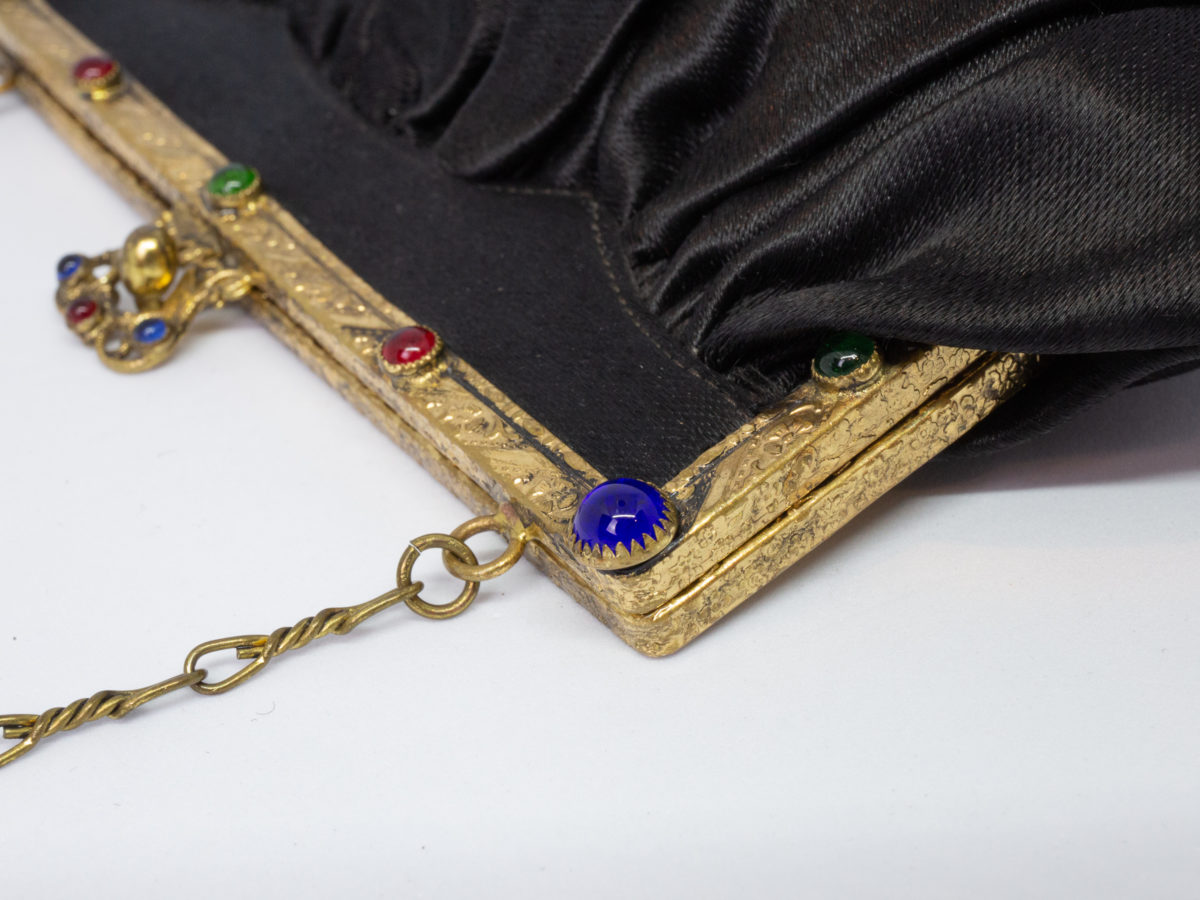 Vintage black satin bag. Very sweet bag in black satin with a gilt metal chain handle and frame studded with coloured stones. c1920s-1930s. In good order for age. Chain drop length approximately 150mm. Close up photo of some of the coloured stones at one corner of clasp frame.