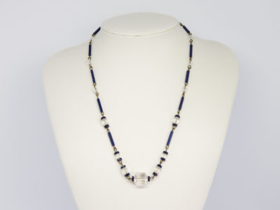 Vintage Art Deco crystal glass necklace. Subtly sparkly handmade clear and navy crystal bead necklace linked with brass throughout. c1930. Clasp not original. Main photo of necklace displayed on a stand seen face on.