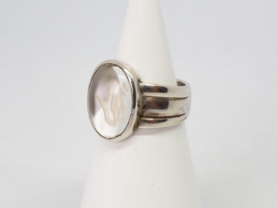 Modern vintage ring in sterling silver with Om crystal. An unusual modern vintage sterling silver ring set to the centre with smooth oval quartz crystal with the Om symbol carved into it. Crystal area measures 18mm by 10mm. Ring size P / 7.5 Photo of ring on a cone shaped display stand with ring front facing left of photo.