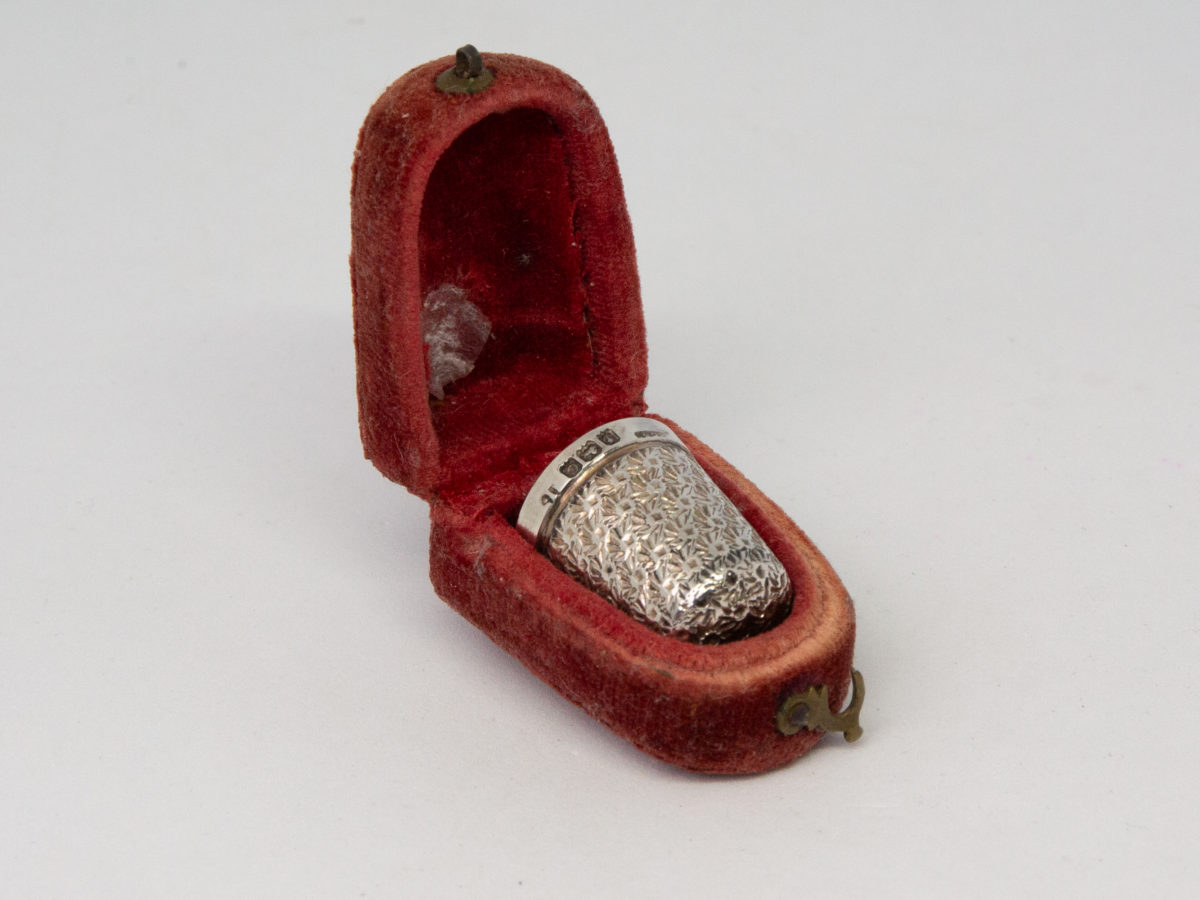 Sterling silver thimble in a fitted velvet case. Lovely sterling silver thimble in a fitted red velvet case with clasp. Fully hallmarked to the side of the thimble for c1927 Birmingham assay. Considerable wear to the velvet case. Thimble measures 20mm long and 16mm in diameter at opening. Thimble weight 2gms. Main photo of thinmle displayed in its fitted red velvet case and shown diagonally with case lid open to the top left of picture