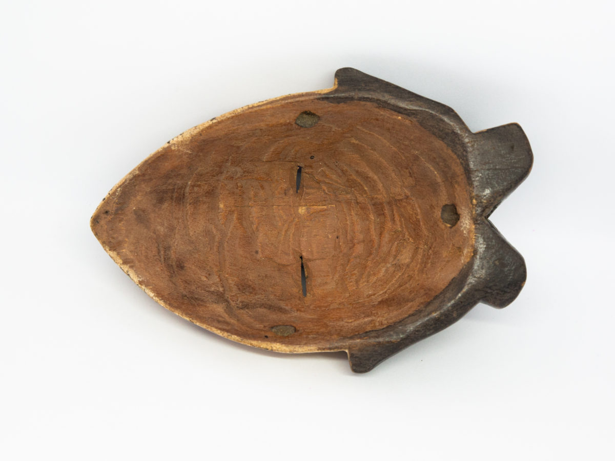 Small vintage wooden African mask. Lovely African mask carved from one piece of wood and coloured in natural pigment. Has a sweet smiling facial expression-even looks as though it is blowing kisses from certain angles- and an unmistakeable aroma of bonfires. Photo of the back of mask showing the natural wood and carving marks.