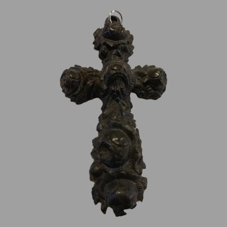 Min photo of cross shown from the front. It is intricately carved with a floral design and the 4 points have rounded ends. The cross has a carved looped at the top with a silver ring added.
