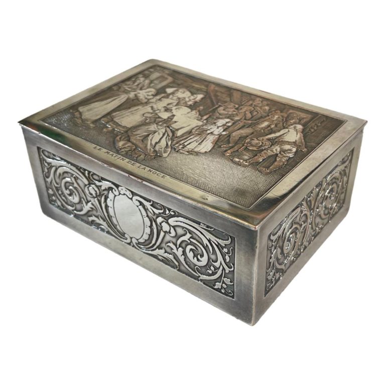 Main photo of French silver plate jewellery box set at an angle showing length, width and top of box. The opening side is facing bottom left corner. This is a beautifully crafted piece of plate ware with a lot of fine detail. Scroll work to the sides and an elaborate scene of people attending to a bride. Needless to say, this box would make a lovely wedding gift - even with the worn silver plate.