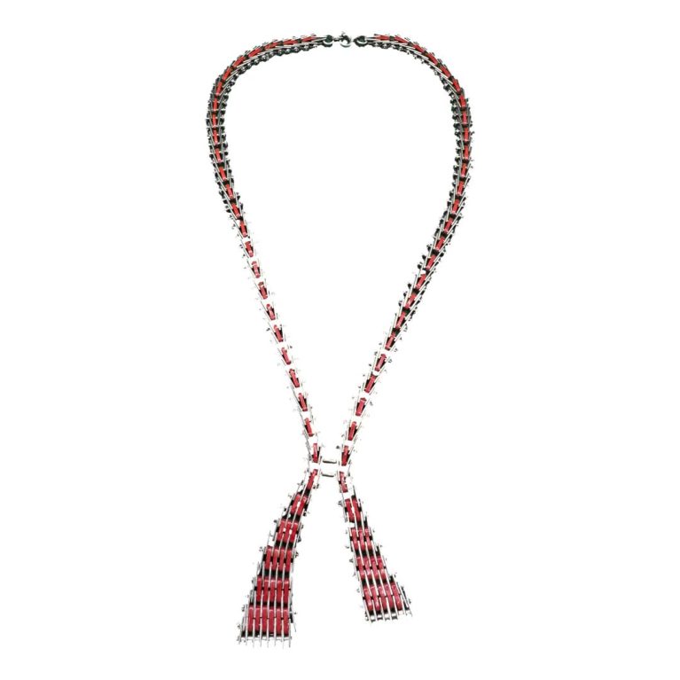 Main photo of necklace in its entirety. There is some green tints to the necklace which is just a reflection of the background used when photographing. Although the necklace gives an impression of a ribbon with loose ends, it is very steampunk in its creation almost like something put together in a garage using nuts and bolts with red enamel embellishment!