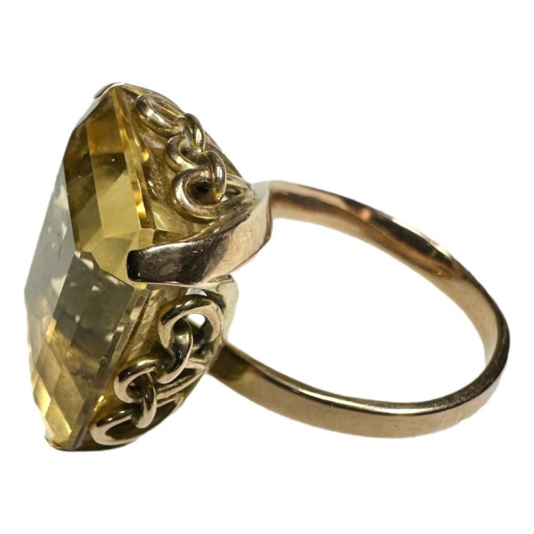 Main photo of ring seen from a raised side angle showing the elaborate setting for the large stone.