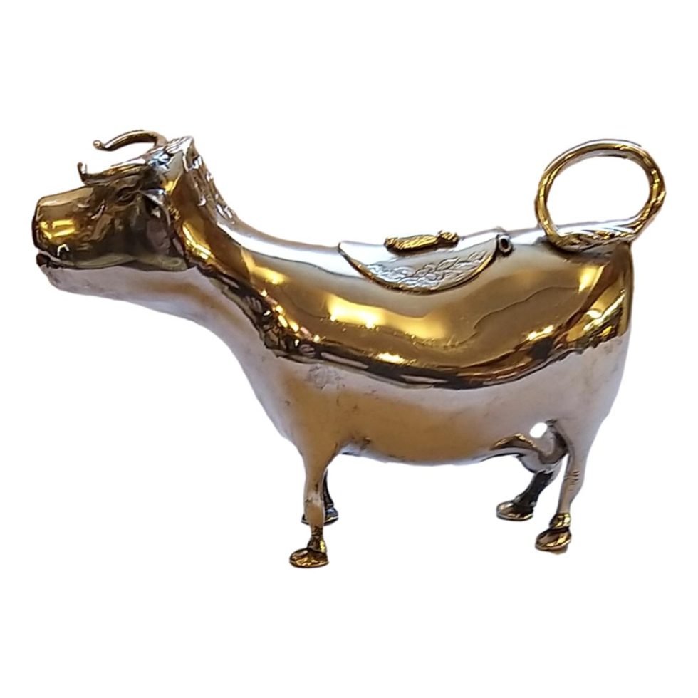 Main photo of creamer seen from the side with cows head to the left of photo. The tail is curled up forming a hoop which acts as a handle.