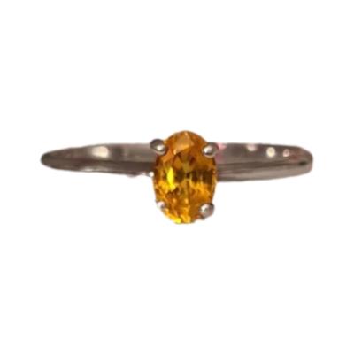 9ct white gold fancy yellow orange sapphire solitaire ring, Features a single oval cut and claw set deep yellow/orange sapphire which can look more orange in some light. Fully hallmark with the rock and 375. Birmingham assayed anchor mark. Weight 1.6 grams. Main photo of ring with light shining on the sapphire showing a vibrant orange colour.