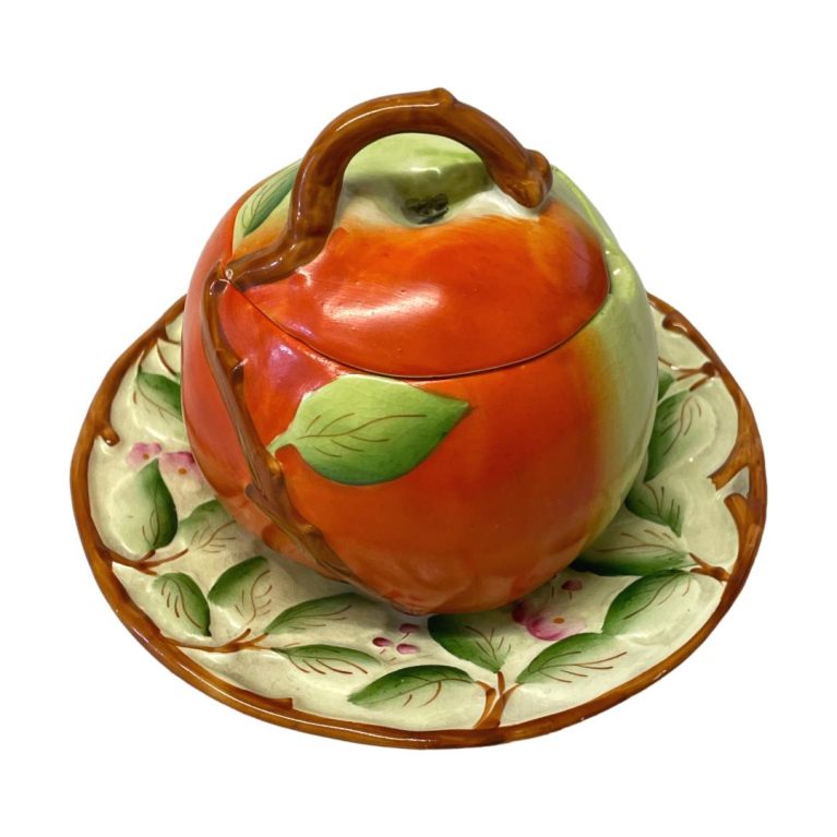Main photo of preserve pot seen from a raised eye level angle with red side of apple with leaf in the foreground.