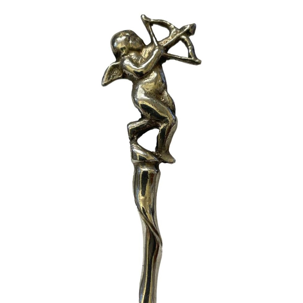 Close up photo of the cherub at the tip of handle. He has his arrow poised to shoot skyward to the top right.