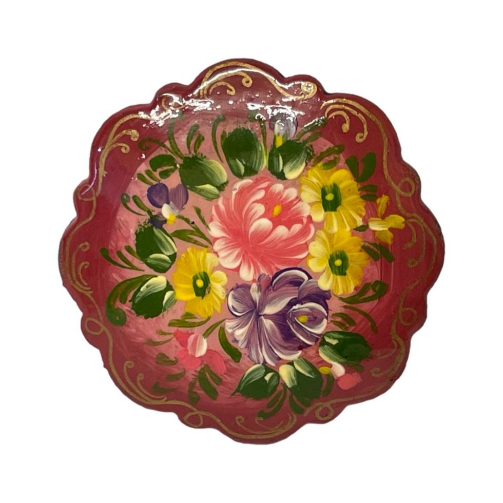 Main photo of brooch front. The base colour is a deep pink with flowers in yellow, purple, lighter pink and with green leaves.