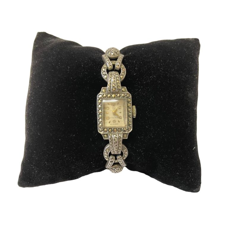 Main photo of watch displayed on a black velvet cushion and showing the watch face and part of the marcasite band.