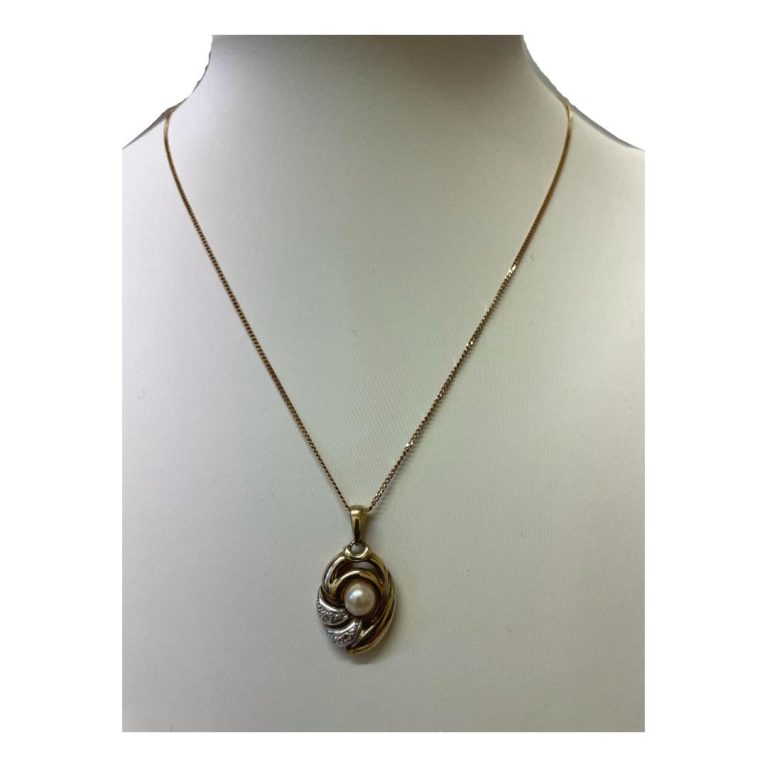 Main photo of pearl diamond pendant &chain on a display stand and shown straight on from the front. The pendant has an unusual design, ovular in overall shape , 2 thirds in yellow 9 karat gold which houses the pearl and other third in 9 karat white gold housing the 2 small round cut diamonds. The pendnt is not a solid piece but rather perforated in lines.