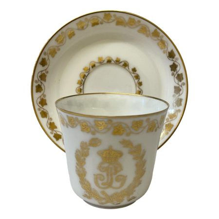 Main photo with cup placed in front of the saucer which is displayed upright on a stand. The decorated side of cup (opposite end to handle) is shown.