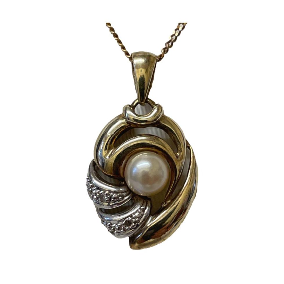 Close up photo of the pendant area. Pearl is in the centre of an unusual gold setting which is an oval shape with the bottom left corner in white gold housing the small diamonds.