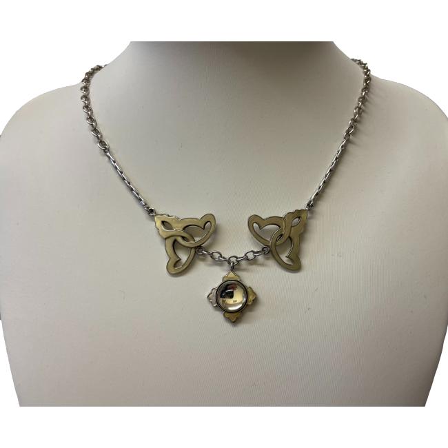 Main photo of Nouveau style Lalique necklace displayed on an off white display stand with necklace front forward facing. The centre piece for the necklace is a Lalique glass dome with short metal arrow head like shapes at 12, 3, 6 and 9 o'clock positions. The glass dome is like a convex glass mirror. A short chain extends from the central pendant which attaches to bell shaped Celtic knotwork pieces with the wider end closest to the pendant. The chain which is attached to the top tip of these is a tight link chain which turns into a regular chain part way up.