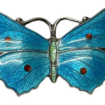 Antique sterling silver and enamel butterfly brooch. Stunning butterfly brooch with turquoise blue enamel wings with red dots and a pale lime green abdomen. Hallmarked sterling silver across the top of wings at the back and makers stamp for John Atkins & Sons and number 1087 on back of lower wings. c1910. Close up photo of the central part of the butterfly showing the vibrant colours of the enamel.