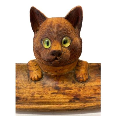 Antique ( circa 1900 -1920 ) Black Forest carved wood Cat inkwell and pen tray with glass eyes. It still has its original internal glass bottle but internally there is some black ink staining to wood. Close up photo of the cat looking straight at the camera.