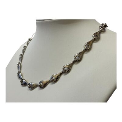 Modern chain in sterling silver. A substantial necklace with unusual links which look like sunflower seeds. Hallmarked 925 for sterling silver to the clasp and first link. Photo of necklace on display stand and shown from a side angle.