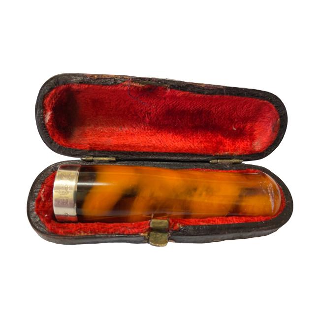 Amber cheroot holder with silver band. Antique cheroot holder with a sterling silver band to the cheroot end. Comes in original fitted case with red velvet lining. Fully hallmarked to the silver band for Birmingham assay c1902. Some wear to outer case. Cheroot holder measures 68mm long. Main photo showing the cheroot holder displayed inside the open case. The cheroot end with the sterling silver band is on the left hand side.