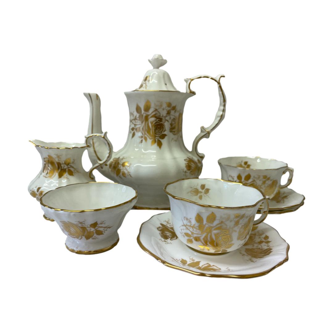 Coffee/tea service for 2 by Hammersley. White and gold set in Golden Glory pattern consisting of a coffee pot, jug, sugar bowl, 2 cups and 3 saucers (1 spare!) Very elegant set in white with gold roses and trim c1950s. All pieces are in excellent condition with a lovely ringing sound when pinged, no chips, cracks or crazing. Minor gilt wear around jug spout and rim of both tea cups. The pot measures 98mm in diameter at base, 210mm at longest across spout & handle, 145mm at widest and 220mm tall with lid. Sugar bowl measures 55mm in diameter at base, 95mm across top and 53mm tall. Jug measures 55mm in diameter at base, 112mm long at spout and handle, 85mm wide and 112mm at tallest (handle). Cups measure 43mm at base, 96mm across top, 108mm long to handle and 58mm high. Saucers measure 145mm in diameter and 18mm high. Main photo of the whole set; pot to the back with jug and sugar bowl on the left and the 2 cups on the right. The sugar bowl and one cup and saucer are in the foreground.