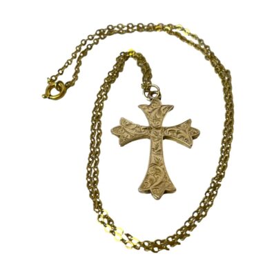 Victorian 9 karat gold cross and chain. Very ornate Victorian 9 karat gold cross engraved with foliate and scrollwork. 9ct hallmark to the back with worn makers initials. Slight dip on the top beam at the back. The cross measures 38mm long and 22mm wide. The chain is hallmarked 9 to the clasp. Main photo of the cross laid on a flat surface with the chain swirled around it.