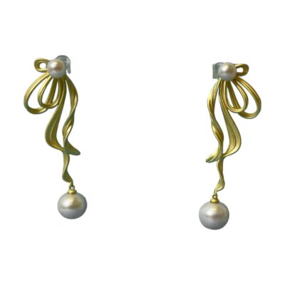 Akoya pearl earrings on gilt silver. Beautiful 18 karat gold plated sterling silver earrings with Akoya freshwater pearls. Lovely design in the style of gold ribbons and accentuated with a large pearl at the ends and smaller pearl at the top 'gathered ribbon' area. Drop length 55mm and 17mm at widest. Main photo of earrings displayed on a stand with the earrings forward facing and shown as would be worn.