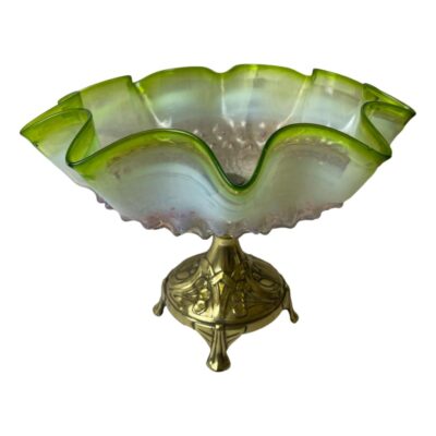 Art Nouveau tazza. Gorgeous tazza with a four footed brass base embossed with tulips and nasturtium leaves. The wavy edged bowl is of multi coloured glass with pink bottom, milky light blue mid section and finished in a vibrant bright green rim. The bowl measures 265mm across the top and 135mm foot to foot at the base. Min photo of the tazza seen from a near eye level angle. The colours of the glass bowl is visible with the wavy edges. The brass base looks very small in ratio to the glass bowl.