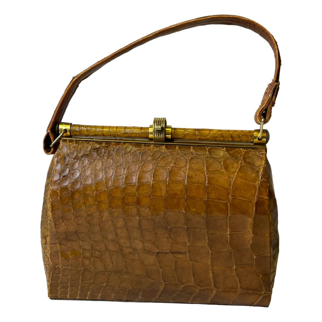 1940s French crocodile skin handbag. A stylish vintage French handbag in crocodile skin with a clever shut and clip brass clasp and a small inner pocket to either side. In a well loved condition with some signs of wear. Still very useable and fashionable! Drop length from top of handle 330mm. Main photo of bag shown from one side with the handle extended above.