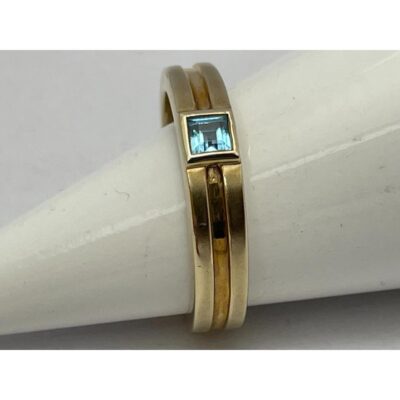 Vintage 9 karat gold and aquamarine ring. A simply elegant 9 karat gold ring with a beautiful princess cut aquamarine as its focus. Ring size L.5 / 6. Main photo of ring displayed vertically on a cone shaped stand which is laid sideways with the aquamarine seen upward facing to catch the light.