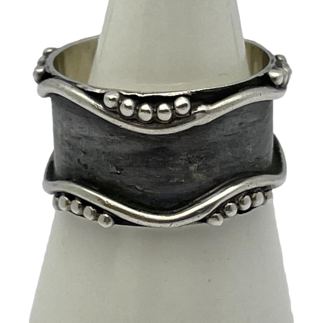 Modernist style sterling silver ring. Unusual ring in a Modernist style with oxidised silver (black) base. Finished with a wavy line to the top and bottom and accentuated with silver dots to the outside of the wave dips. Great thumb ring. Ring size Q.5 / 8.25. Main photo of ring on a cone shaped stand with a dip wave at the top and bottom. There are 5 dots in top dip and 5 dots either side of bottom upward wave. The oxidised black silver main area around the centre of the ring is striking in contrast to the silver.