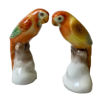 Pair of Macaw birds by Herend. Sweet pair of colourful macaws in shades of orange, brown & green on white stands. The birds are hand-painted so not identical which adds extra charm to these fine porcelain birds. Stamped Herend Hungary to the base, each bird measures approximately 70mm tall, 37mm at widest and 30mm at widest. Main photo of birds placed facing each other with one on the right slightly in the foreground.