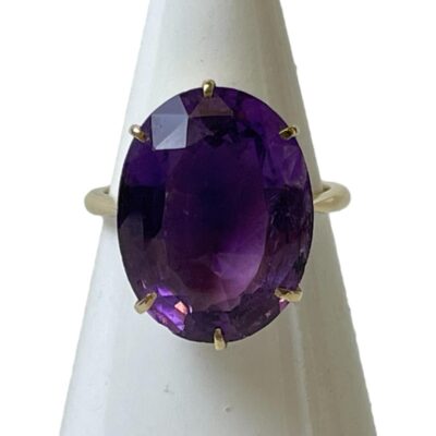 Vintage 9 karat gold ring with amethyst. Large oval cut amethyst set on unmarked 9 karat gold. Amethyst measures approximately 18mm long by 24mm wide. Ring size P.5 / 8. Weight 5.6 grams. Main photo of ring displayed on a cone shaped stand and seen with ring front forward facing.