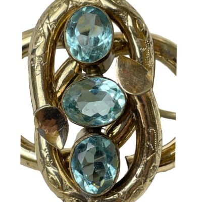 Victorian brooch with faux aquamarine. A striking Victorian pinchbeck brooch set with 3 pale blue oval cut faux aquamarines. Lovely metal working of the brooch frame in an intertwined figure of eight like pattern. Close up photo of the centre of the brooch showing the stones and pattern on the pinchbeck bands around the stones.