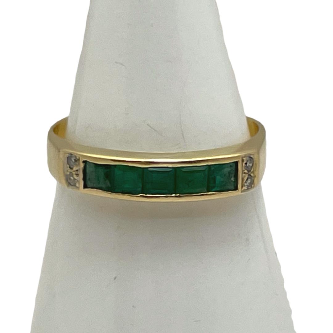 18 karat gold with emeralds and diamonds. Modern look ring set with 5 square cut emeralds in a row with 2 very small round cut diamonds to either end. Hallmark is very worn & barely visible but tested as 18 karat gold. There are one or two small chips to a couple of the emeralds which does not detract the fine quality of the ring. Ring size P / 7.5. Main photo Of ring displayed on a cone shaped stand and seen with ring front forward facing. The 5 square cut emeralds are in a horizontal row left to right with 2 small round cut diamonds on either end vertically.