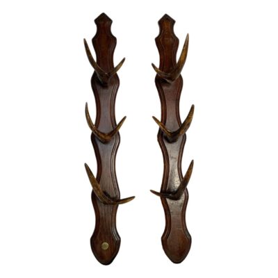 Pair of wall racks by Saint-Étienne. A vintage pair of wall mounting racks with small antler 'hooks' originally used for holding guns. Original brass button for Saint-Étienne armoury manufacturers to the base of one rack. Each rack measures approximately 600mm long with width of wood at 70mm. The small antlers, varying in size, are graduating with largest pair at the bottom with a depth of approximately 120mm. Small split to the wood on one rack at top near screw hole however the backs have metal reinforcement to the top & bottom which double as slot hooks. Main photo of the racks shown side by side with the rack with brass button on the left. The wooden mounts are long and slender with the smaller antlers to the top graduating to the largest at bottom.