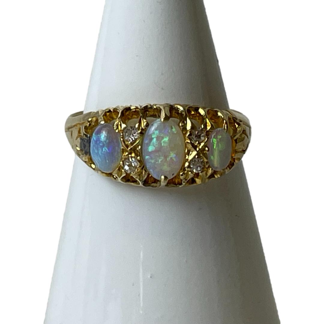 Antique 18 karat gold ring with opals. A stunning ring set with 3 colourfully alive opals with largest to centre. Two tiny round cut diamonds separate each opal. Fully hallmarked to inside band for Birmingham assay c1915 and made by S. Blackensee & Son Ld. Ring size M.5 / 6.5. Main photo of ring on cone shaped display stand with the ring front forward facing. The largest of the 3 opals is in the centre with 2 small diamonds either side followed by the smaller opals at either end.