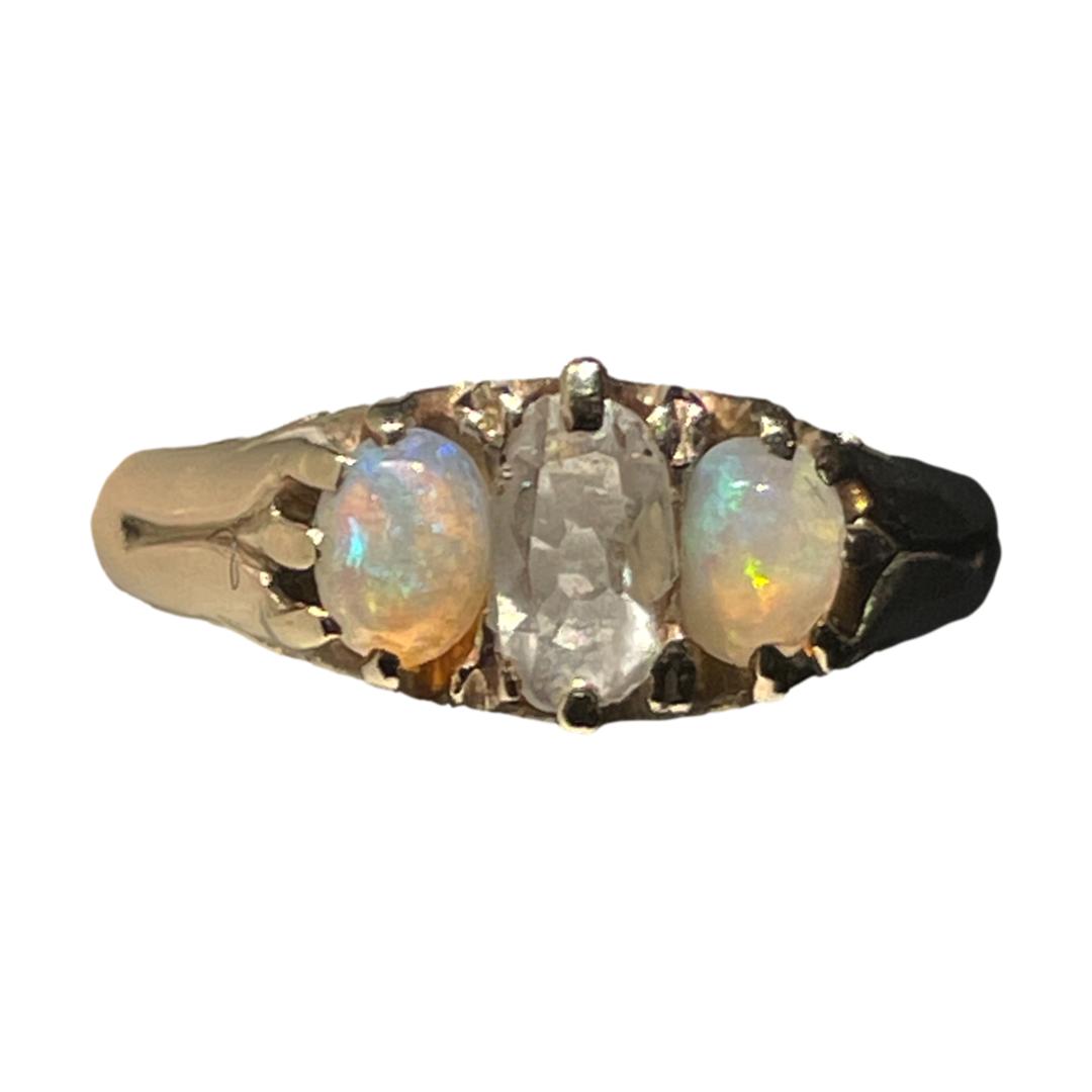 Victorian ring with diamond and opals. Stunning antique ring set with an old cut oval diamond to the centre with an opal cabochon to either side. The opals have lovely colour play with one mainly in green and other blue with flashes of pink, orange & yellow. The ring is unmarked and has been tested as 18 karat gold. Size N / 6.75. Weight 3.2grams. Main photo of ring on a flat surface with ring front forward facing. There are a multitude of colours in the opals.