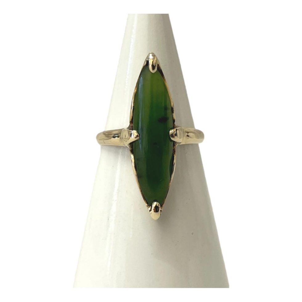 Main photo of 10kt gold jade ring displayed on a white cone shaped stand with the ring front forward facing. The jade is a lovely shade of apple green with some flecks included and is set vertically so a long thin ring which would suit long slender fingers.