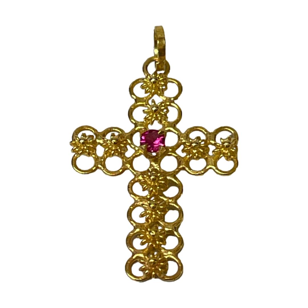 Main photo of 18kt gold ruby cross displayed upright and against a white background. The single ruby at the centre of the cross is a lovely deep pink colour which compliments the intricate gold work of this sweet piece.