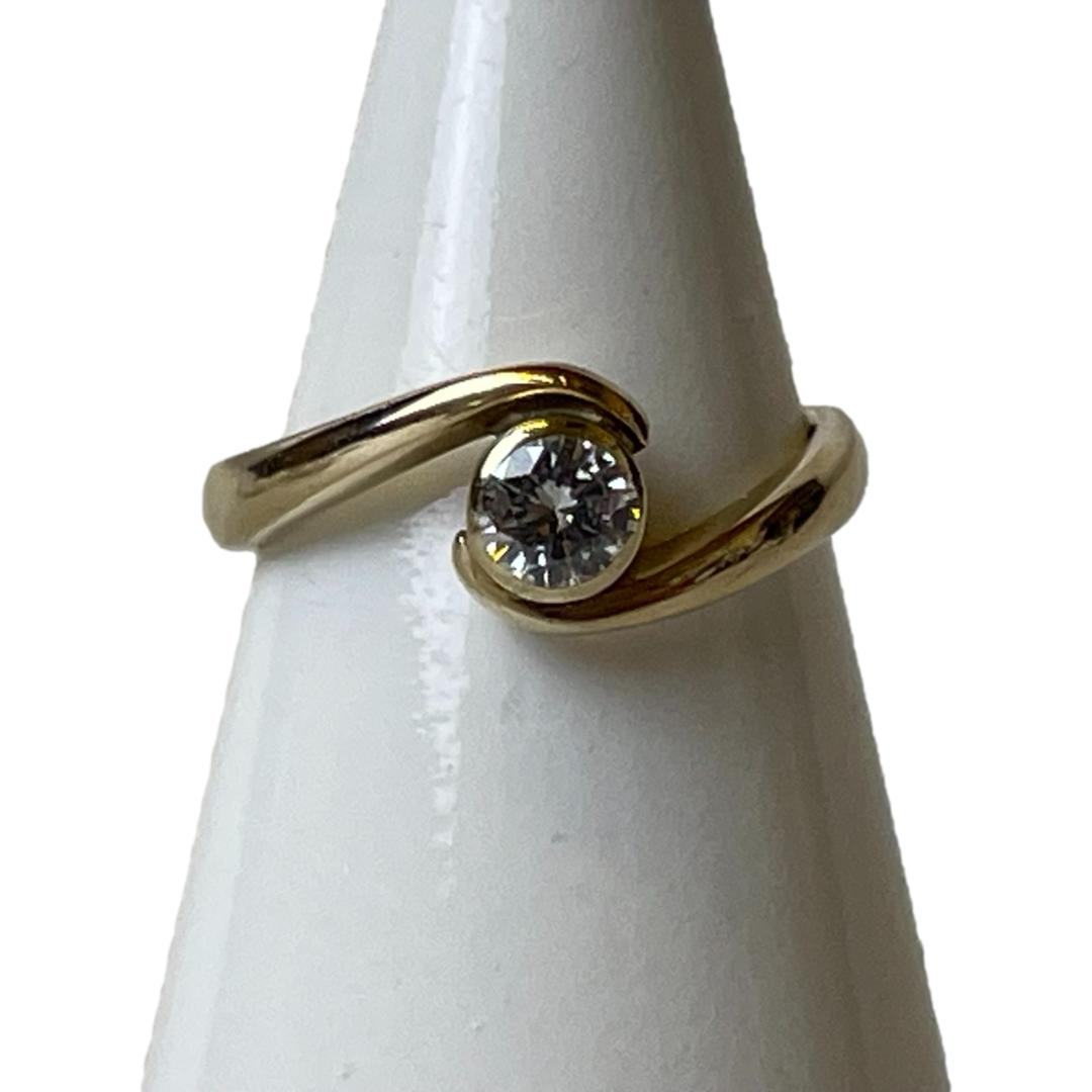 Main photo of vintage gold diamond ring displayed on a white cone shaped display stand and seen with the ring front forward facing. The lefthand band goes over the diamond whilst the righthand band travels under. Lovely simplistic yet strikingly effective design.