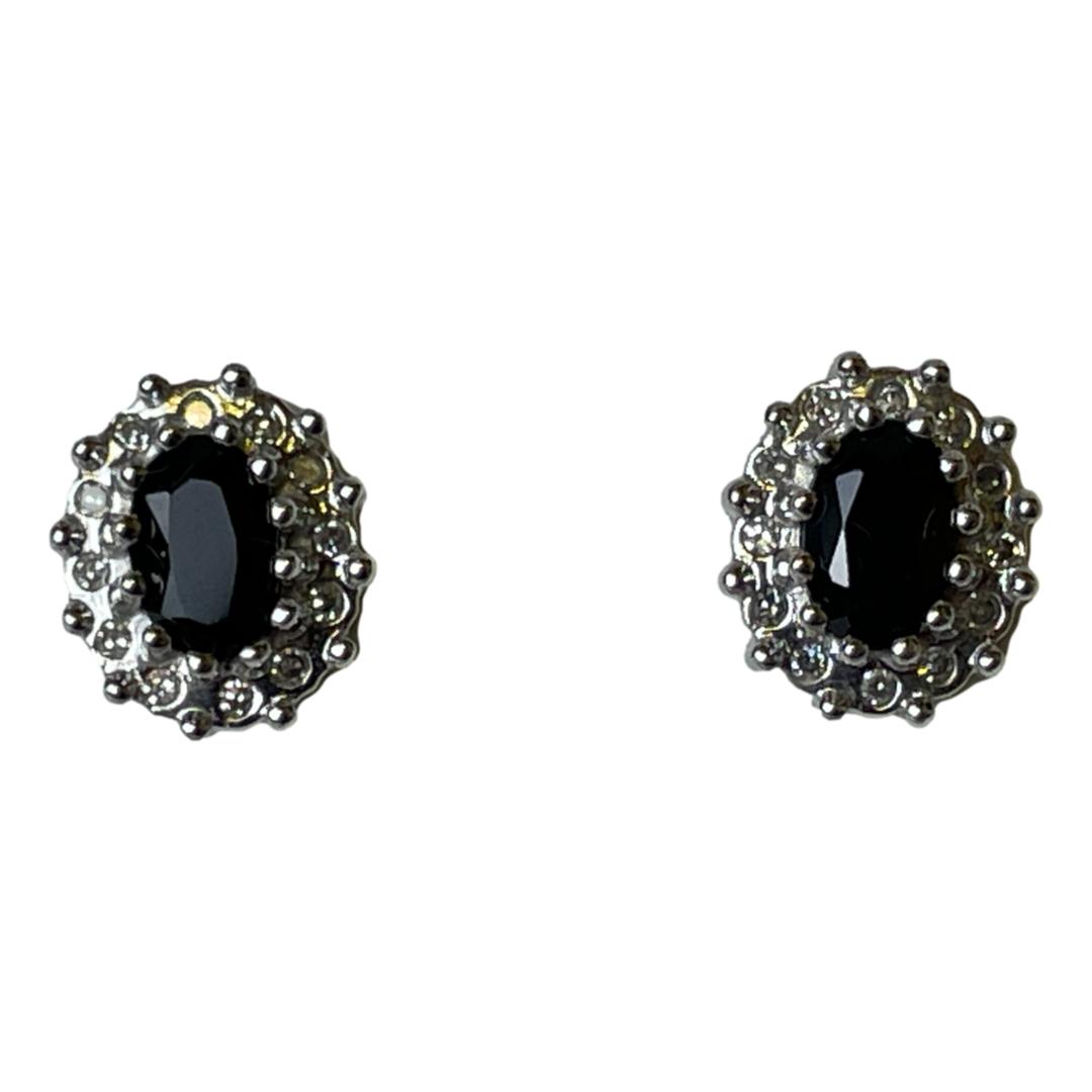 Main photo of gold diamond sapphire stud displayed side by side again st a white background with the stud fronts only on display. The sapphires are an intense blue colour and oval in shape with 12 small round cuts diamonds framing them.